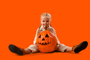 Poster - Cute little girl dressed for Halloween as scarecrow with pumpkin on orange background