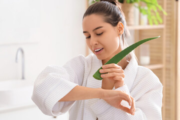 Wall Mural - Beautiful young woman in bathrobe applying aloe vera at home