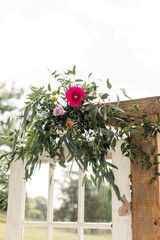 Wall Mural - Close-up of wedding arch decorated with greenery and vibrant flowers.