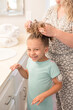 © Cavan Images - Little girl getting her hair put up in a pony tail by her mother