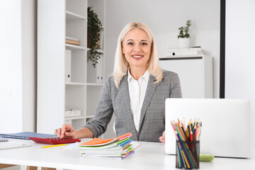 Wall Mural - Mature female Math teacher using calculator at table in classroom