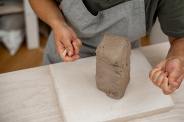 Cutting off the necessary piece of clay before forming a pottery product. Learning how to cut clay on ceramics workshop. Wire clay cutter to cut clay from a large block.