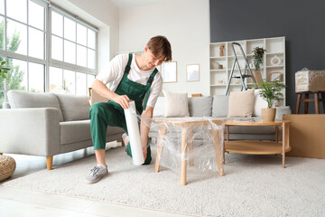 Wall Mural - Male worker wrapping table with stretch film in room