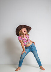 Wall Mural - Little girl in cowboy hat and jeans isolated on white background.