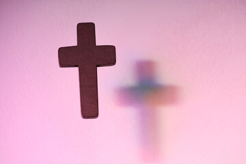 Wall Mural - Wooden cross on pink textured background, space for text. Religion of Christianity