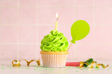 Wall Mural - Sweet Birthday cupcake with burning candle and party whistle on white table