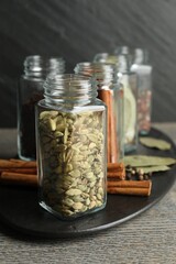 Wall Mural - Different spices in glass jars on grey wooden table, closeup