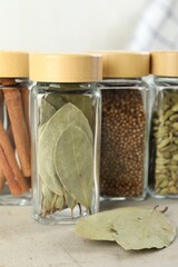 Wall Mural - Different spices in glass jars on light textured table, closeup