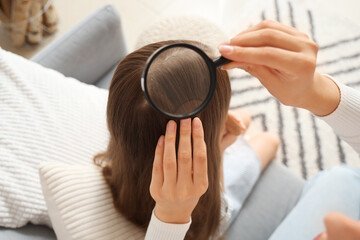 Poster - Mother with magnifier checking her little daughter's head for pediculosis at home, closeup