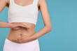 © New Africa - Healthy digestion. Woman holding something near her belly on light blue background, closeup. Space for text