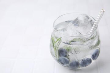 Poster - Refreshing water with blueberries and rosemary in glass on white tiled table, closeup. Space for text