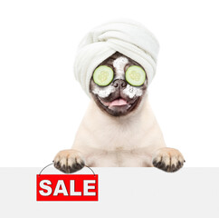Fototapete - Funny Pug puppy with towel on it head and with a piece of cucumber on it eyes holds looking above blank white banner and holding signboard with labeled 