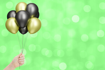 Aufkleber - Female hand holds bunch of red and black balloons on blurred summer green background. Empty space for text