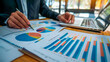 © Hanna - Business Professional Analyzing Charts and Data Insights While Working at Office Desk