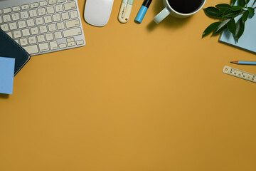 Wall Mural - Office table with keyboard, notebook and cup of coffee on yellow background. Top view with copy space