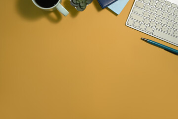 Wall Mural - Top view office table with keyboard, notebook and cup of coffee on yellow background