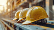 © khonkangrua - Close-up of three yellow construction helmets placed on a construction site beam, emphasizing safety and teamwork.