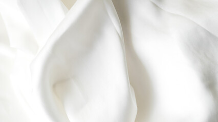 Crumpled white silk fabric background with soft folds and delicate texture.