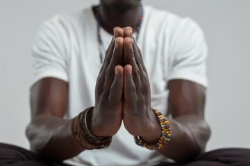 A close-up photograph of a person's hands in a prayer position while practicing yoga.