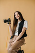 © dsheremeta - A young female photographer with a camera in her hands poses in the studio.