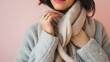© VK Studio - Close-up of a woman’s head and shoulders, warmly wrapped in a cozy light scarf against a soft pink background, reflecting comfort and elegance.