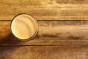 Wall Mural - Glass of beer with froth on wooden table, top view. Space for text