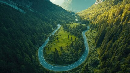 Curved road through a vibrant green forest and mountainous region, seen from above.