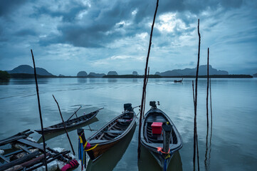 Wall Mural - Traditional wooden fishing boat parked by the sea with moody sky in overcast day