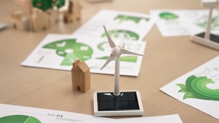 Wall Mural - Windmill model represented using clean energy and wooden block symbolized ecology house. Green power graph scatter on the table business team working to decrease future carbon footprint. Delineation.