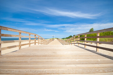 Wooden pathway on a sand beach in bright sunny day