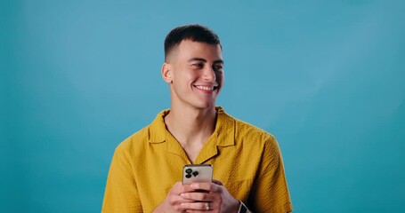 Poster - Happy man, smartphone and laughing for funny joke, social media or meme on blue studio background. Male student, guy and smile on mobile cellphone for fun research, chatting or texting on mockup
