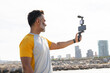 © ADDICTIVE STOCK - Man recording with smartphone gimbal at seaside