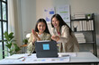 © PaeGAG - Two Young Businesswomen Celebrating Success in Modern Office with Digital Tablet and Documents