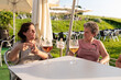 © ADDICTIVE STOCK - Senior women enjoying a conversation over beer outdoors