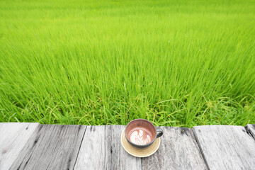 Wall Mural - a cup of Cocoa drink on weathered table with green rice field background