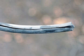 part of an old gray plastic crumpled hose with a hole on the street