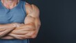 © Chananporn - Close-up of muscular arm and bicep of a man showcasing strength and fitness on a dark background.