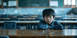 © Aigo labs - A young boy sits alone in an empty classroom, with a sad expression on his face. bullying concept