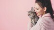 © tantawat - Serene Moment with Beloved Cat - Woman showing affection to pet in soft pink setting, perfect for pet care concept designs. Copy space available.