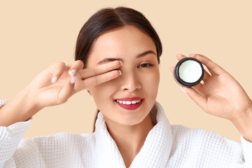 Poster - Pretty young woman with jar of facial cream on beige background