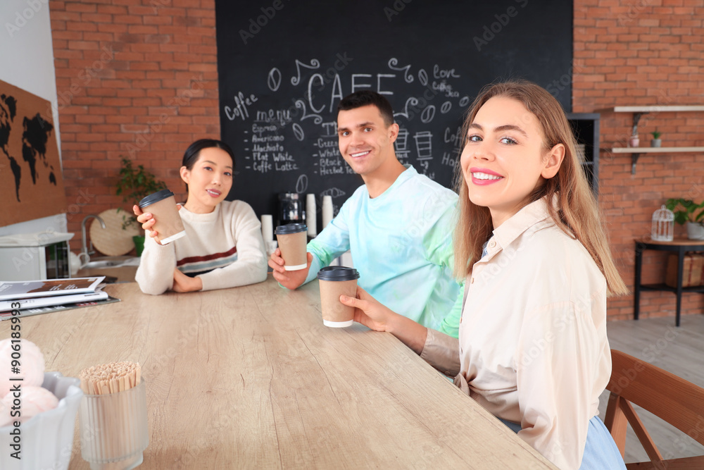 Young people with coffee cups sitting at table in cafe