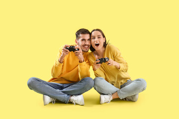 Poster - Happy young couple playing video games on yellow background