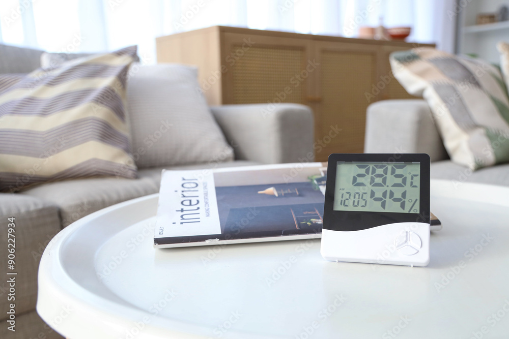Digital hygrometer with magazine on table in living room, closeup