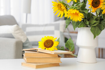 Wall Mural - Vase with sunflowers and books on table in light living room, closeup