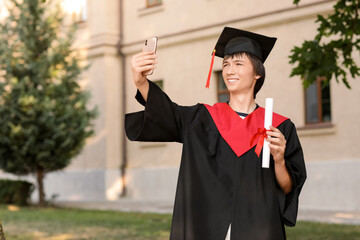 Sticker - Happy male graduating student taking selfie with diploma outdoors