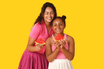 Poster - Beautiful young African-American woman and her cute daughter with pieces of fresh watermelon on yellow background