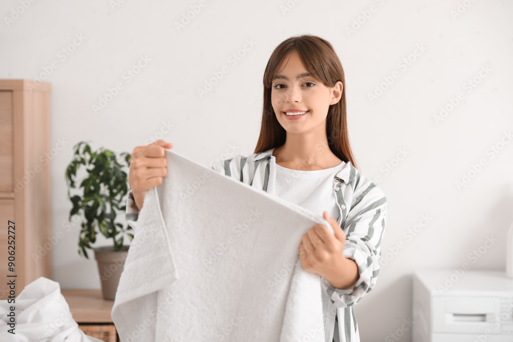 Young woman with clean towel in laundry room