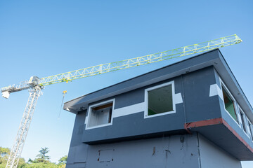 High building construction crane. Construction crane with blue sky background.An old building with windows removed and gutted for demolition below the cranes