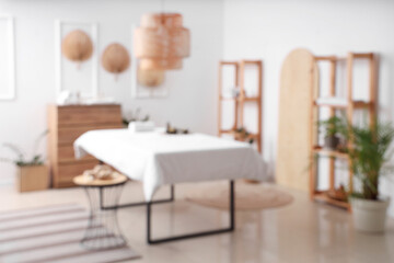 Poster - Blurred view of light spa salon with massage couch, fans and shelf units