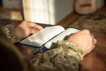 Wall Mural - Hands of soldier in uniform holding the Holy Bible. Natural aesthetic light